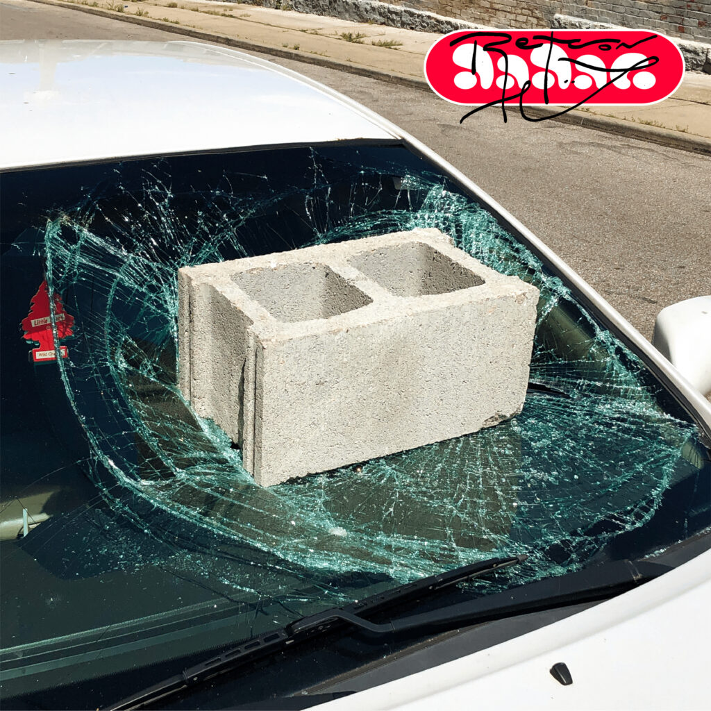 Design featuring a cinder block breaking a car windshield with type overlaid