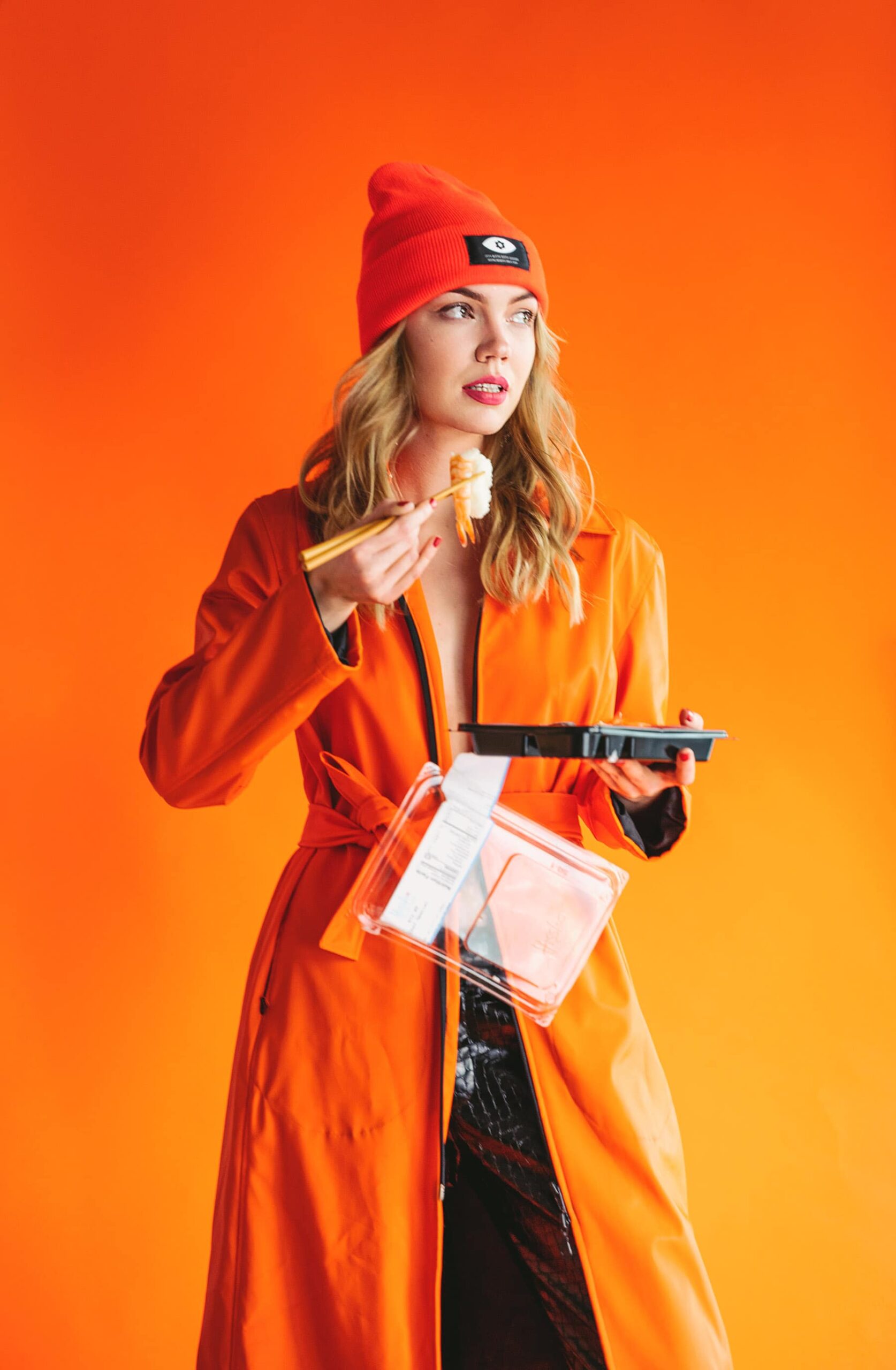 Photograph of a woman in orange coat with container
