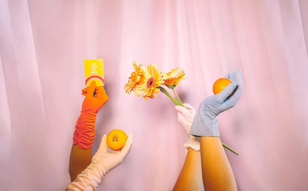 Hands in gloves holding fruits, flowers, and card