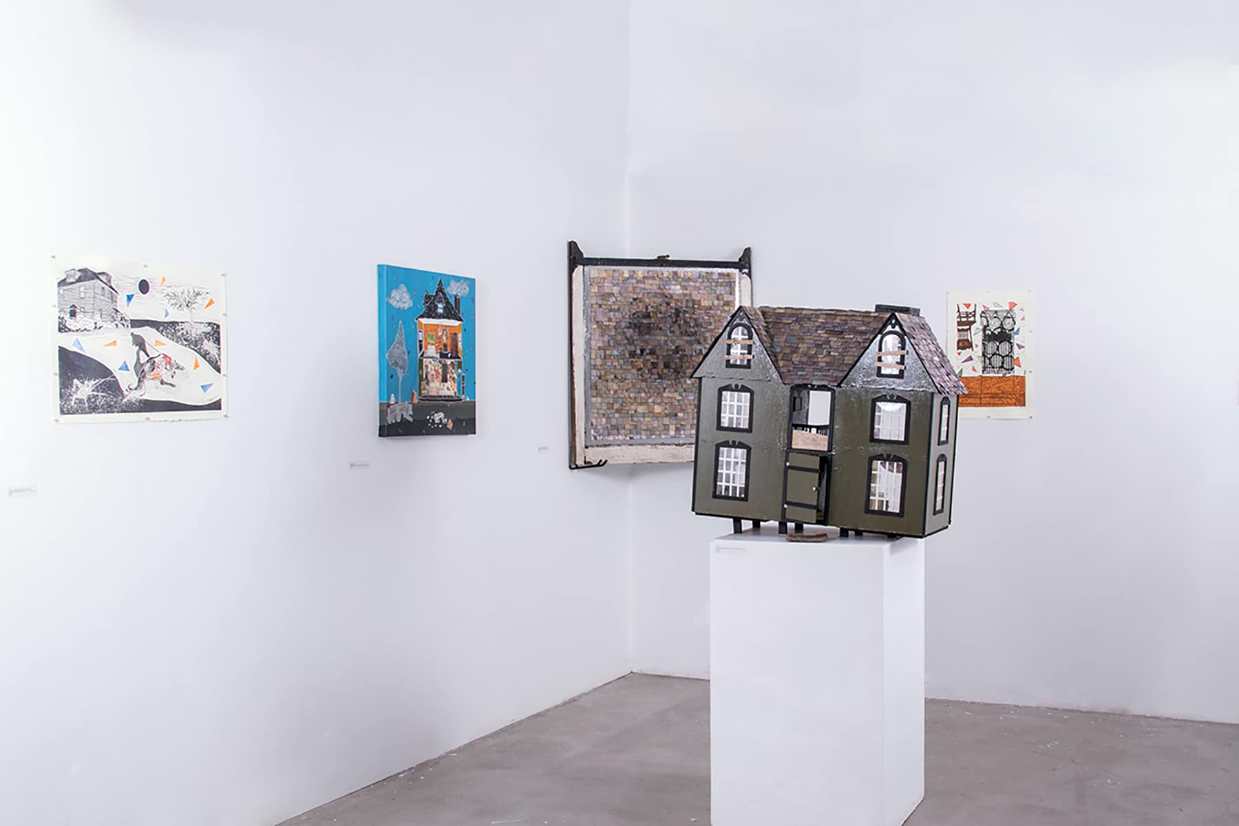 Art installation with pieces on wall and sculpture of house