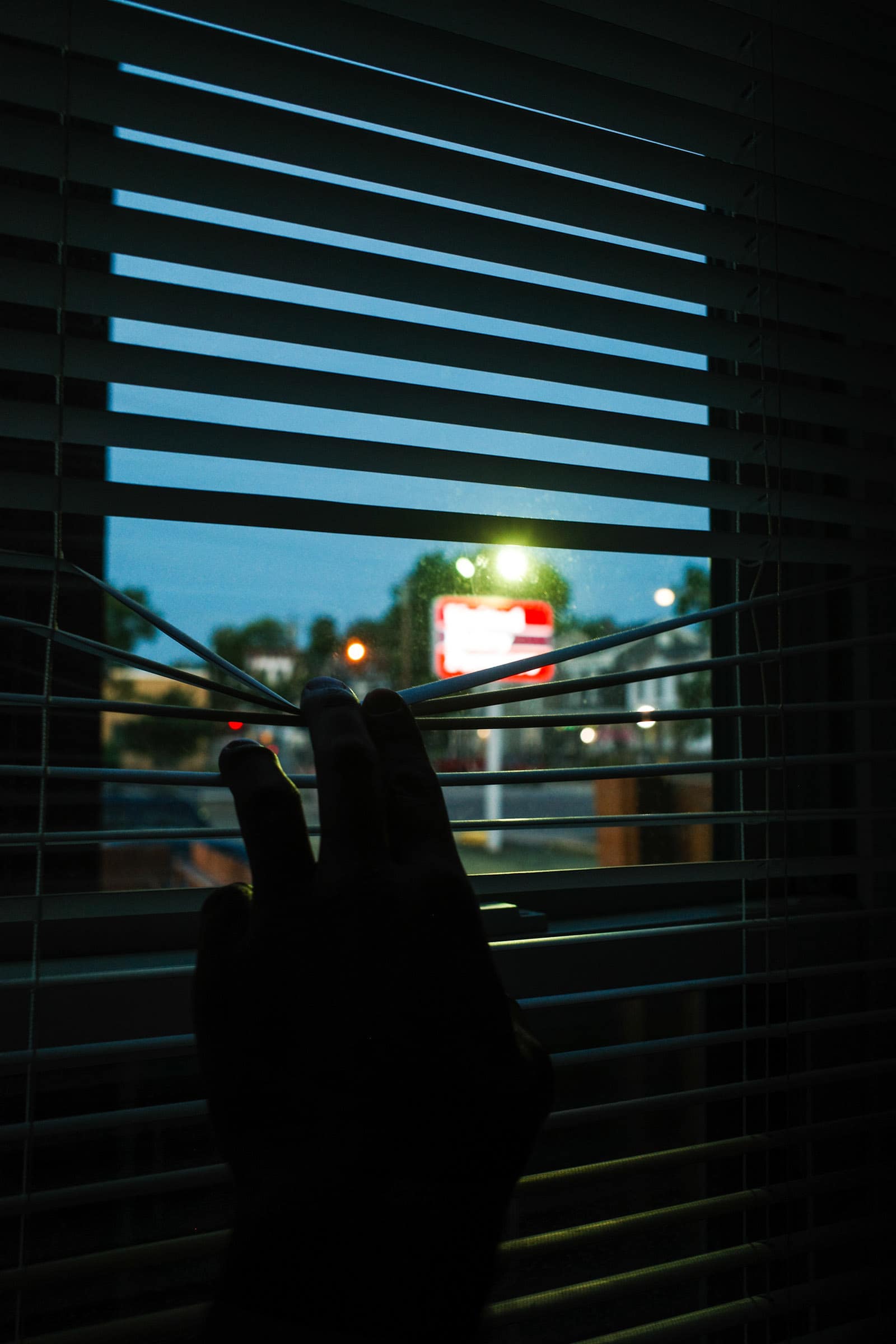 Peeking through blinds at dusk