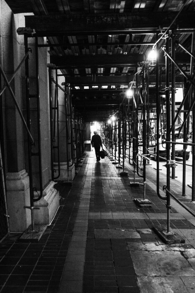 Man walking under scaffolding at night