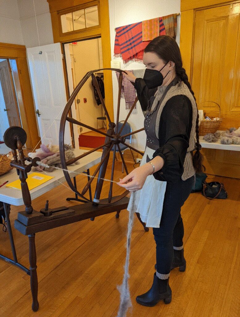 Person at wheel spinning yarn