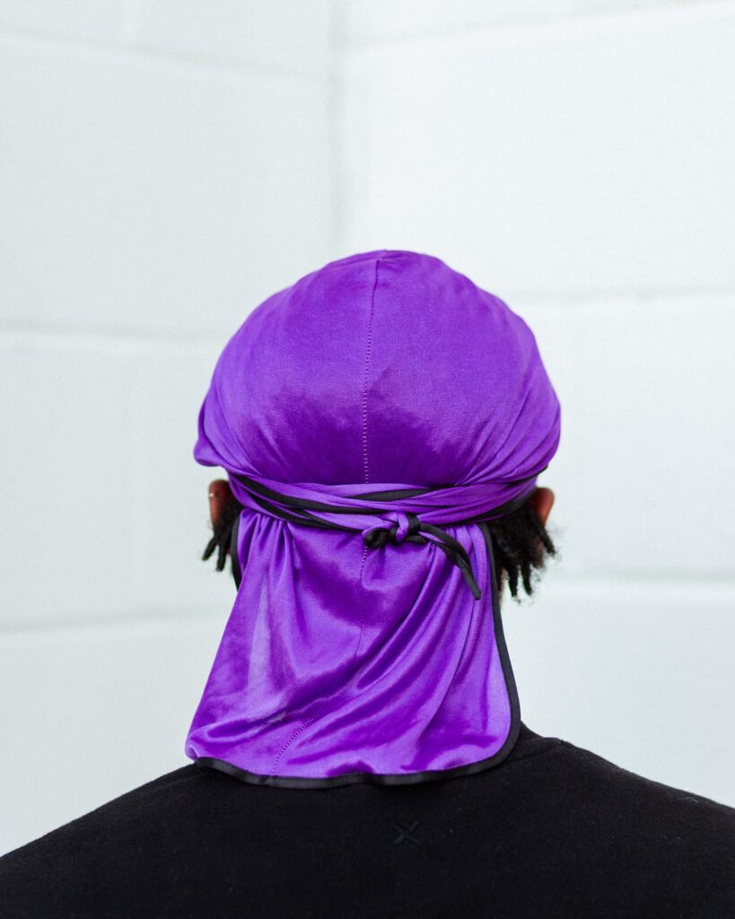 A person in a purple doo rag photographed from behind titled Royalty