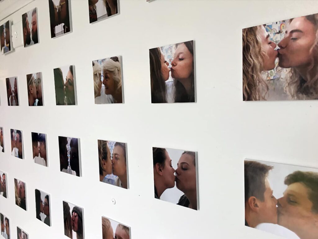photographs of individuals kissing a mirror on a gallery wall